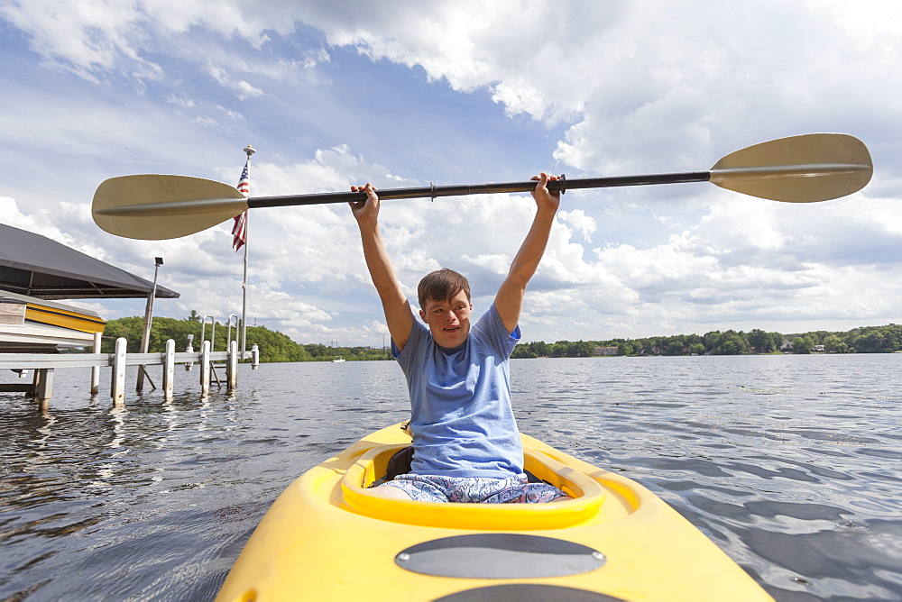 Happy young man with Down Syndrome using a kayak in a lake