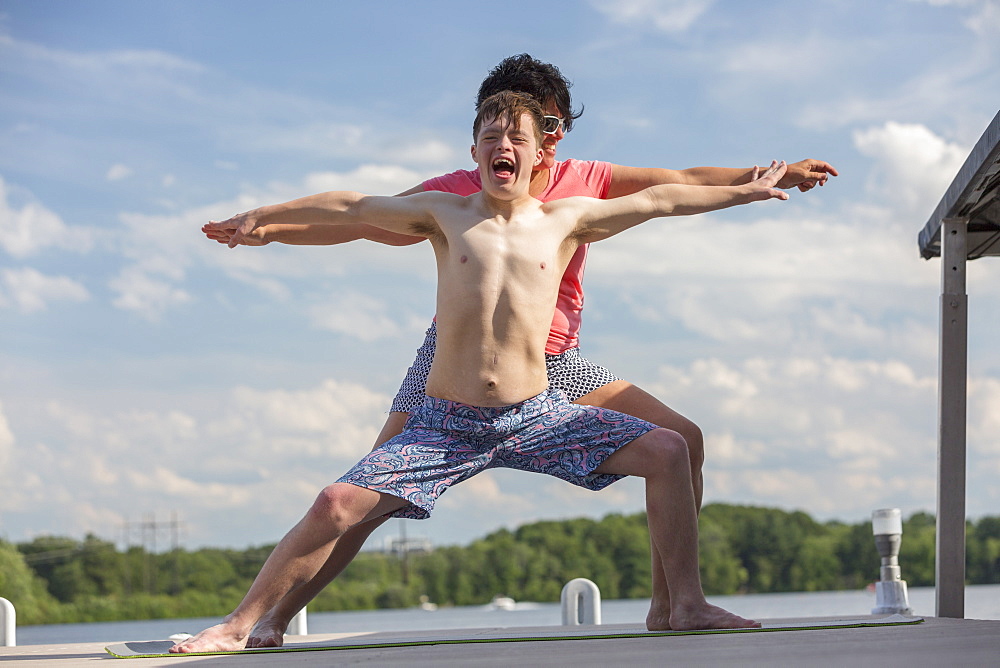 Young man with Down Syndrome exercising on a dock with his friend