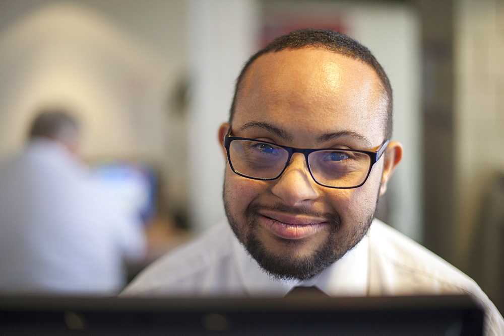 Happy African American man with Down Syndrome as a waiter taking reservations in the computer