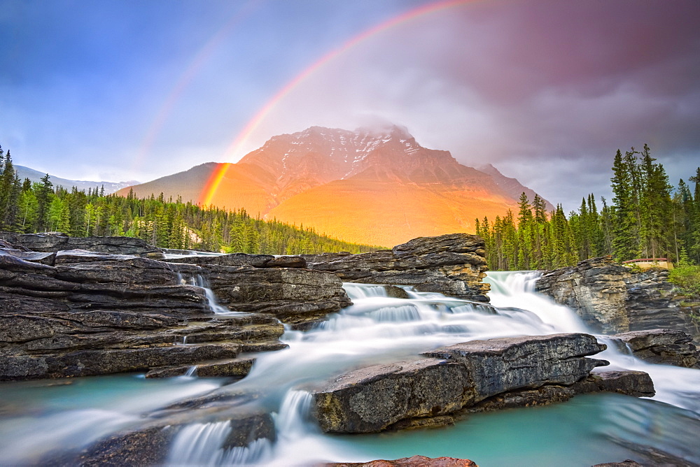 Double rainbow shining over a rugged waterfall and the Rocky Mountains, Jasper National Park; Alberta, Canada