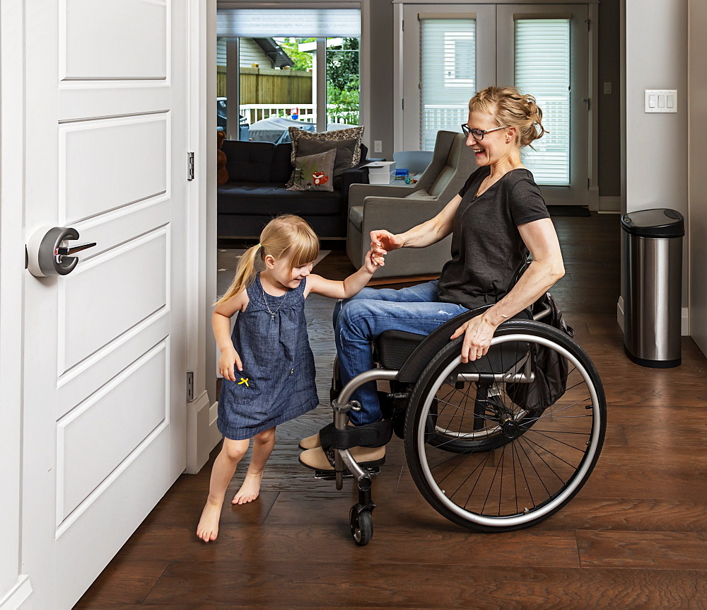 A paraplegic mother dancing with her daughter in the kitchen using her whellchair: Edmonton, Alberta, Canada