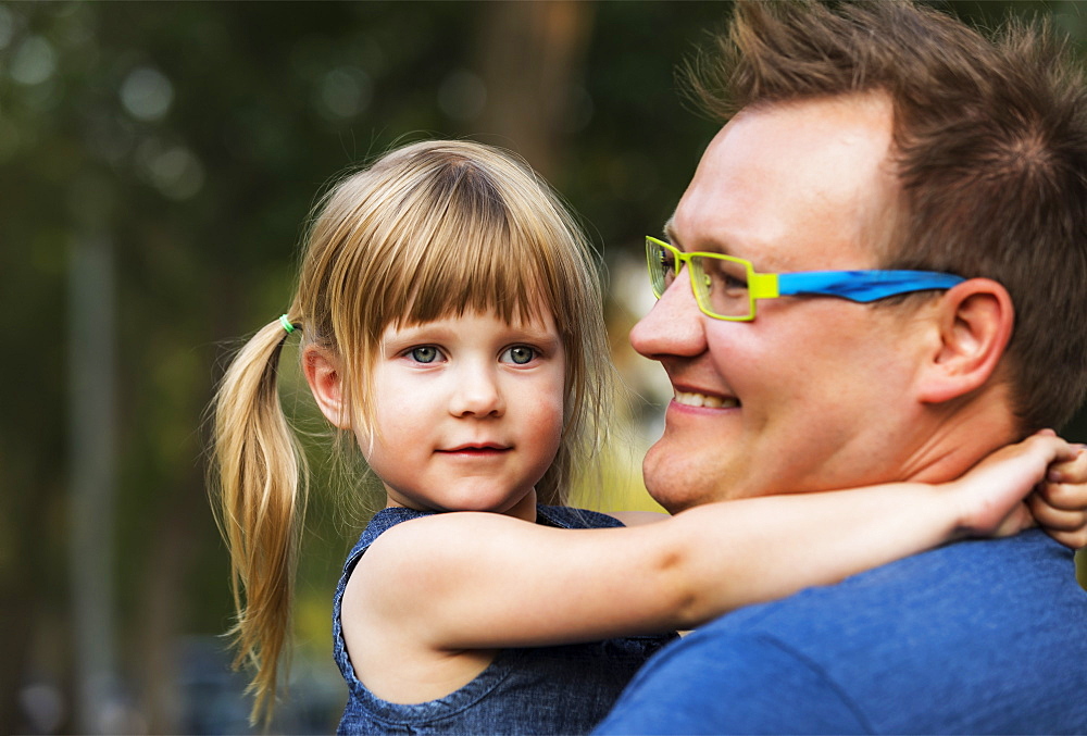 Portrait of a father cuddling with his young daughter; Edmonton, Alberta, Canada