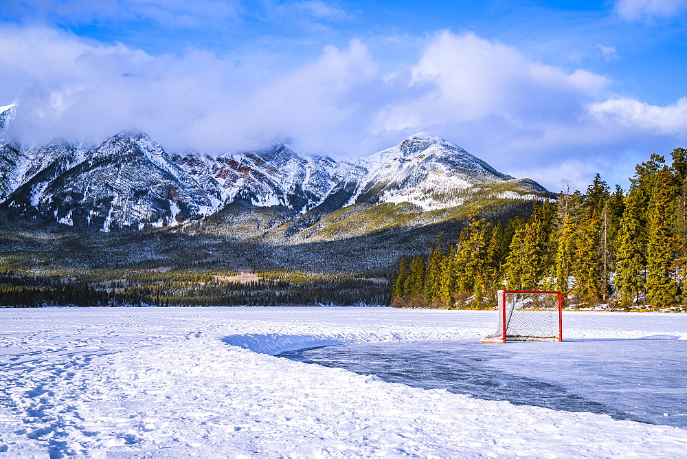 Frozen Pyramid Lake with hockey net on a cleared ice rink in winter, Jasper National Park; Alberta, Canada