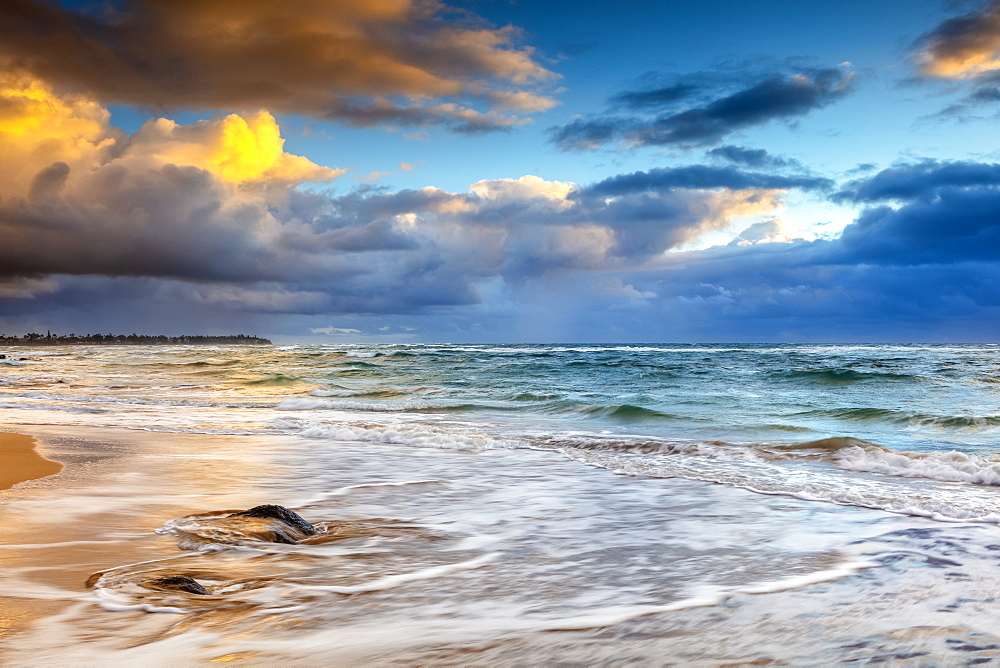 Sunrise over the Pacific Ocean from the shore of Kauai and dark clouds over the horizon; Kauai, Hawaii, United States of America