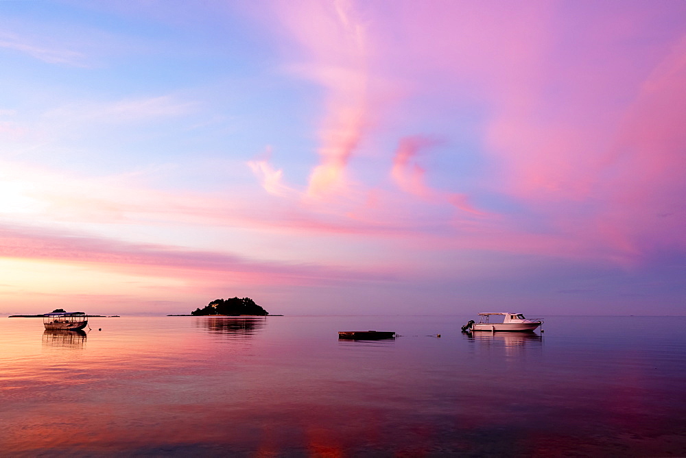 Sunrise over the South Pacific with boats anchored off the shore; Malolo Island, Fiji