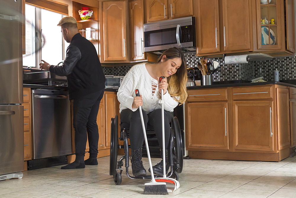 Woman with Spinal Cord Injury sweeping the floor