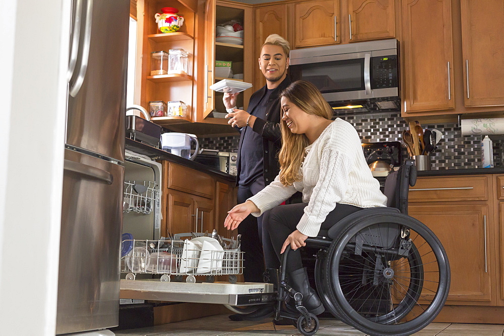 Woman with Spinal Cord Injury arranging dishwasher