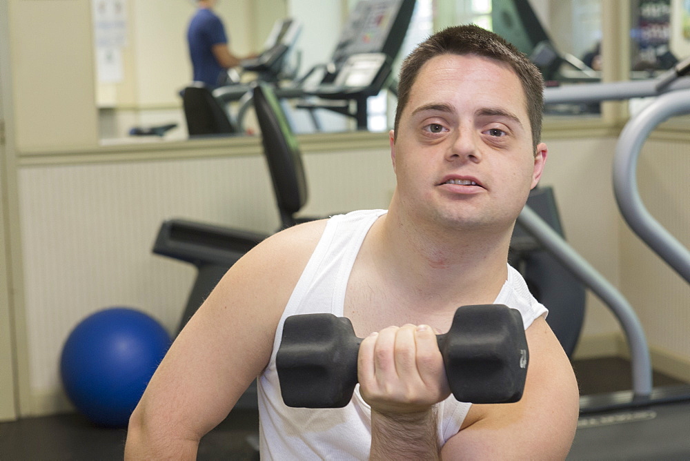 Man with Down Syndrome exercising in a gym with dumbbell