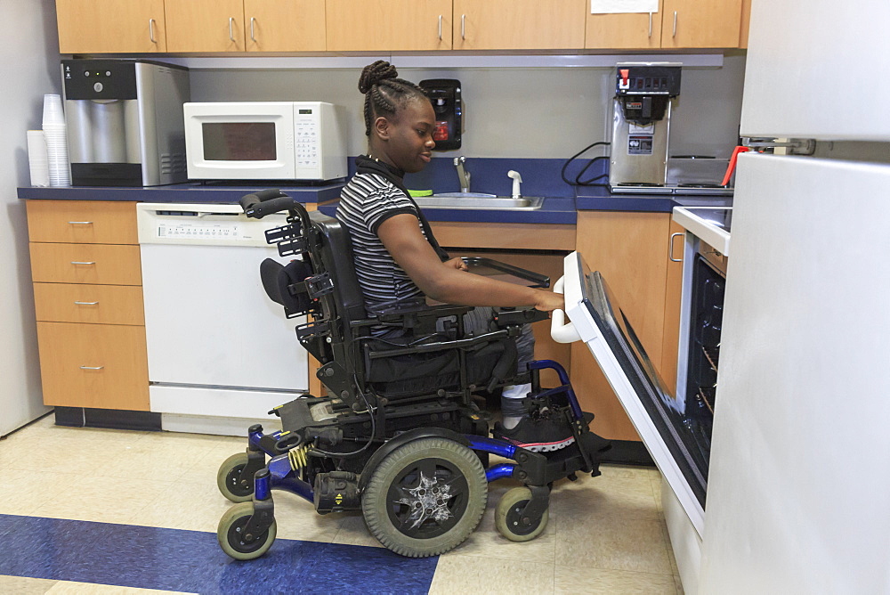 Teen with Cerebral Palsy using oven in the kitchen