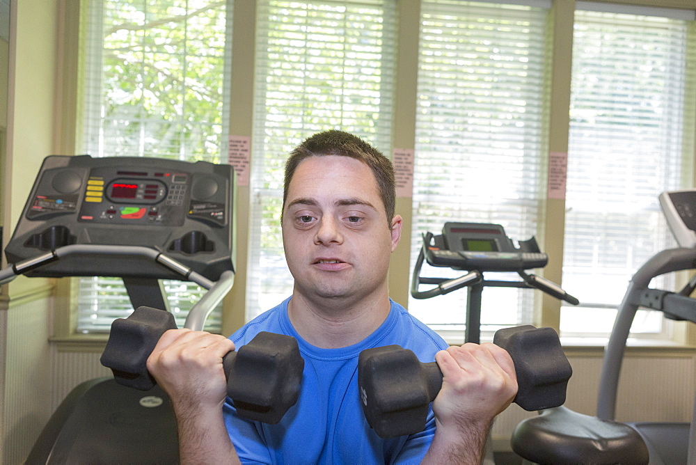 Man with Down Syndrome exercising in a gym with dumbbell