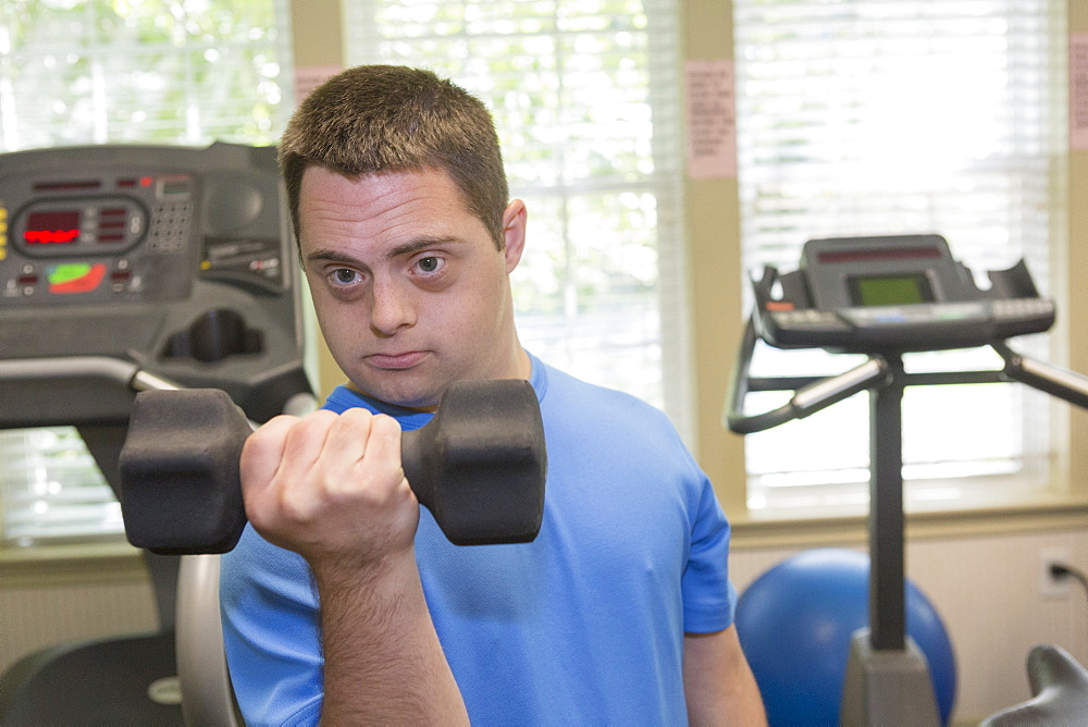 Man with Down Syndrome exercising in a gym with dumbbell