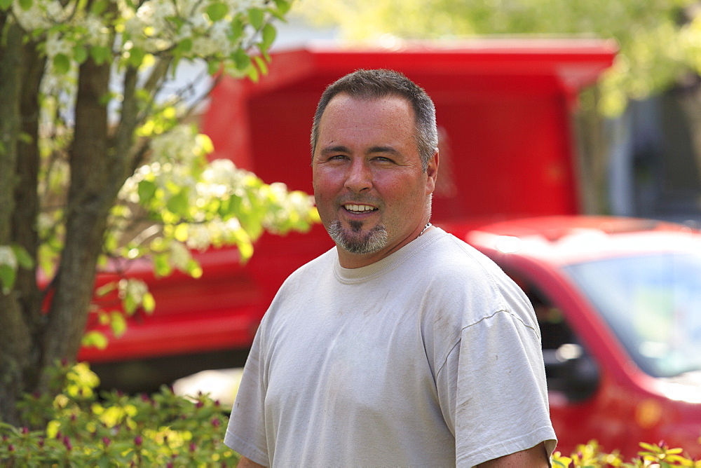 Landscaper in a garden with his truck in the background