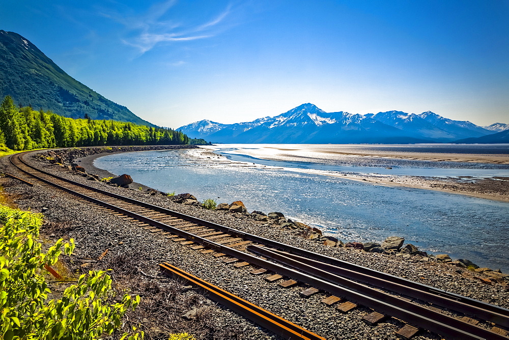 Alaska Railroad track along with Turnagain Arm of Cook Inlet, Chugach Mountains in the background, South-central Alaska in summertime; Portage, Alaska, United States of America