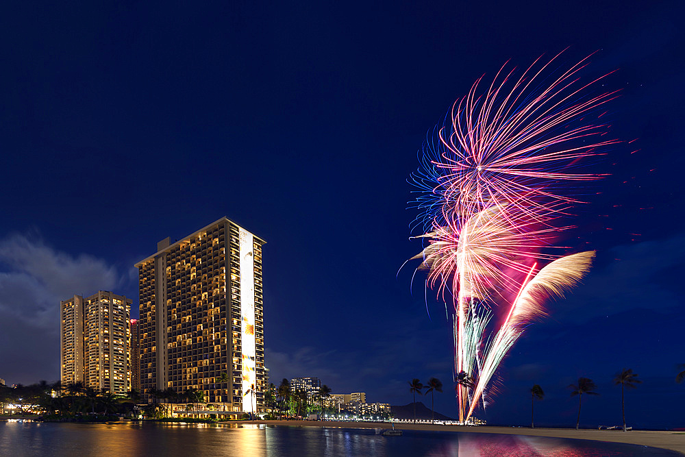 Condominiums and fireworkds along the coastline of Waikiki at sunset; Honolulu, Oahu, Hawaii, United States of America