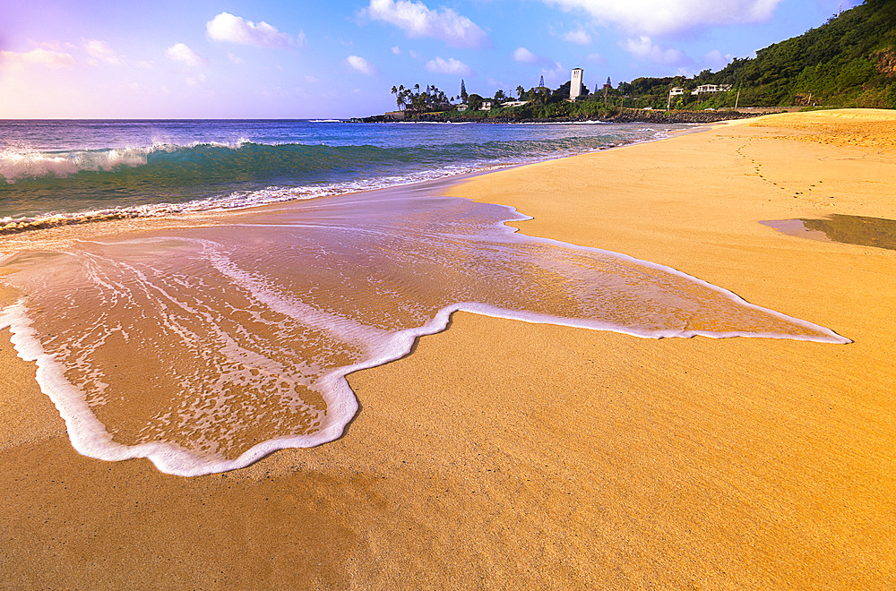 Surf on the golden sand at Waimea Bay Beach Park at sunrise; Oahu, Hawaii, United States of America