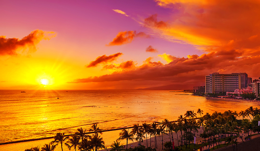 Condominiums and palm trees along the coastline of Waikiki at sunrise; Honolulu, Oahu, Hawaii, United States of America