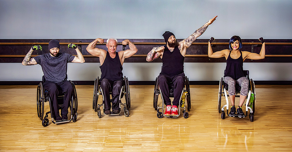 A group of paraplegic friends fooling around showing their muscles after a workout in fitness facility: Sherwood Park, Alberta, Canada