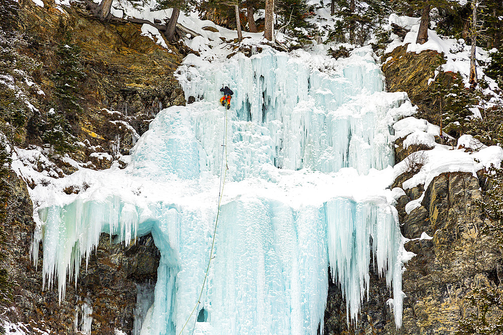 Ice climber on frozen waterfalls on a cliff of a mountain, Banff National Park; Lake Louise, Alberta, Canada