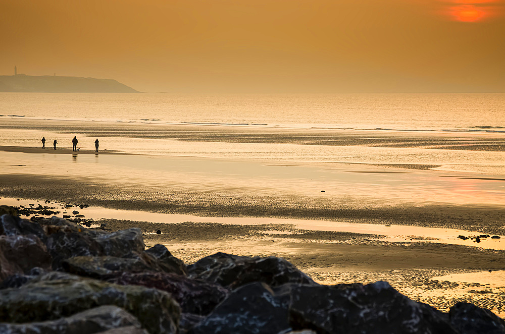 A family walks at sunset on a deserted beach in Northern France; Wissant, Nord Pas de Calais, France