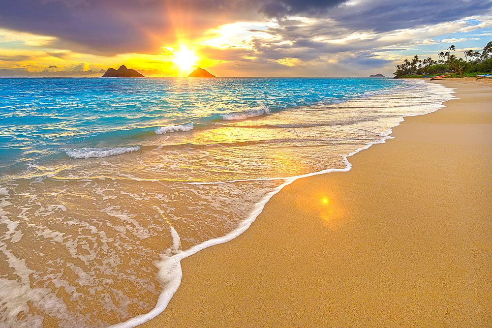 Lanakai Beach at sunrise, with the surf washing up on the golden sand and a view of the Mokulua Islands in the distance; Oahu, Hawaii, United States of America