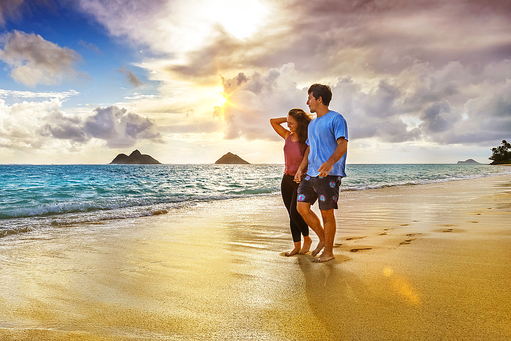 A couple walks on Lanakai beach on the Hawaiian island of Oahu at sunset; Lanakai, Oahu, Hawaii, United States of America