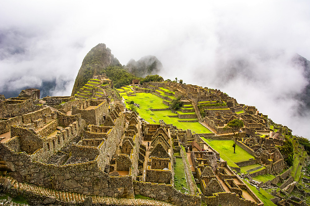 The sacred city of Machu Picchu sunlit and enveloped in low clouds; Cusco, Peru