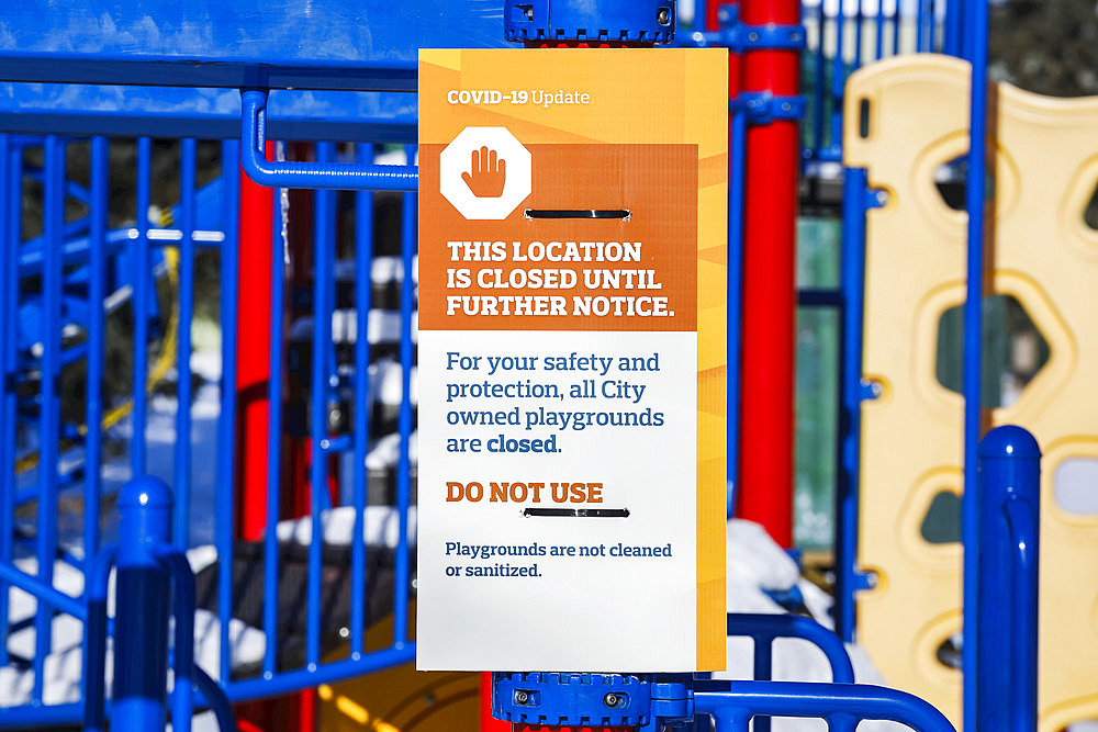 A sign at a playground cordoned off with caution tape during the COVID-19 World Pandemic; Edmonton, Alberta, Canada