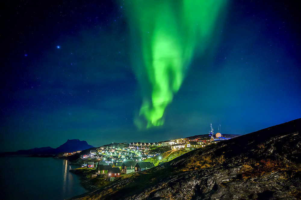 Northern Lights over the glowing city of Nuuk; Nuuk, Sermersooq, Greenland