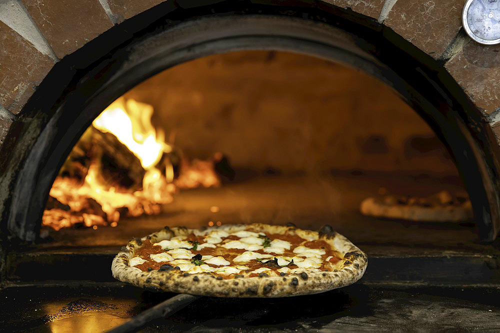 Margherita pizza being pulled from a wood-fired pizza oven; Melbourne, Victoria, Australia