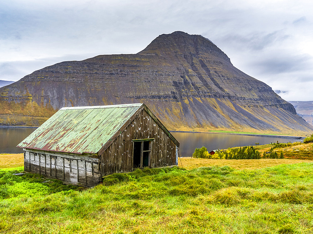 Weathered building on the water's edge of a fjord in Northwestern Iceland in the municipality of Isafjarourbaer; Isafjarourbaer, Westfjords Region, Iceland