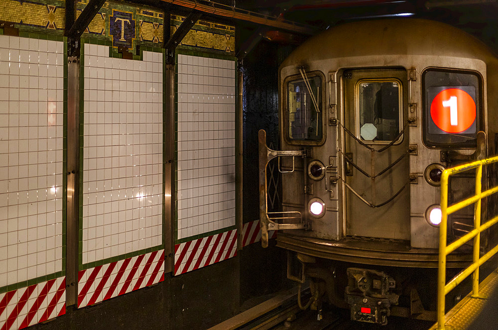 Subway underground on tracks beside tiled wall, Manhattan; New York City, New York, United States of America