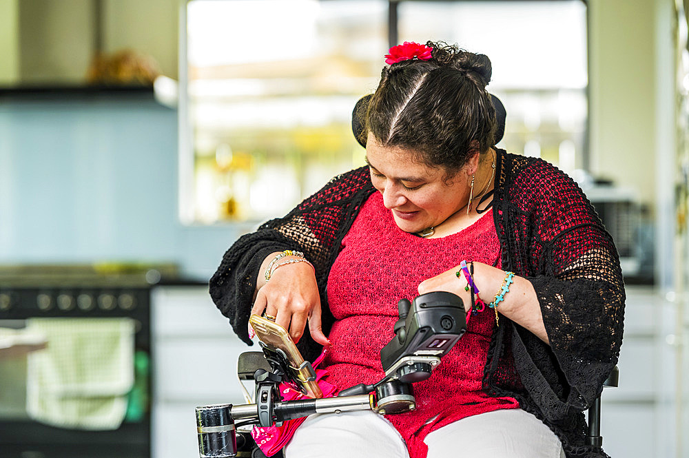 Maori woman with Cerebral Palsy in a wheelchair using a smart phone; Wellington, New Zealand