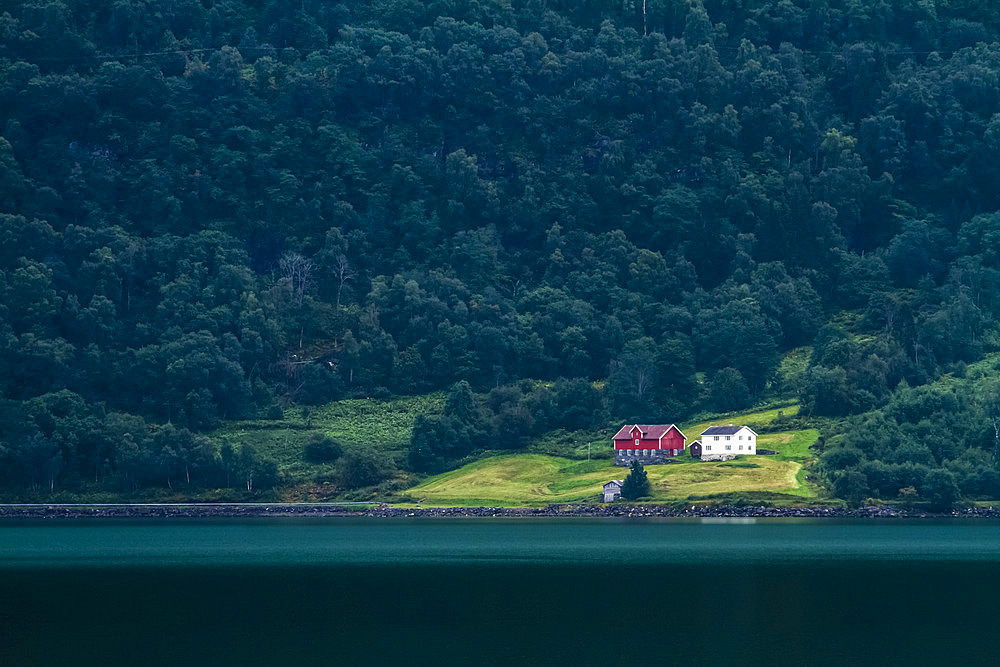 Isolated Norwegian house by a lake, surrounded by a dark forest; Norway