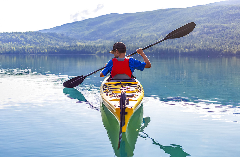 A teenage boy kayaking on White Lake, White Lake Provincial Park; British Columbia, Canada