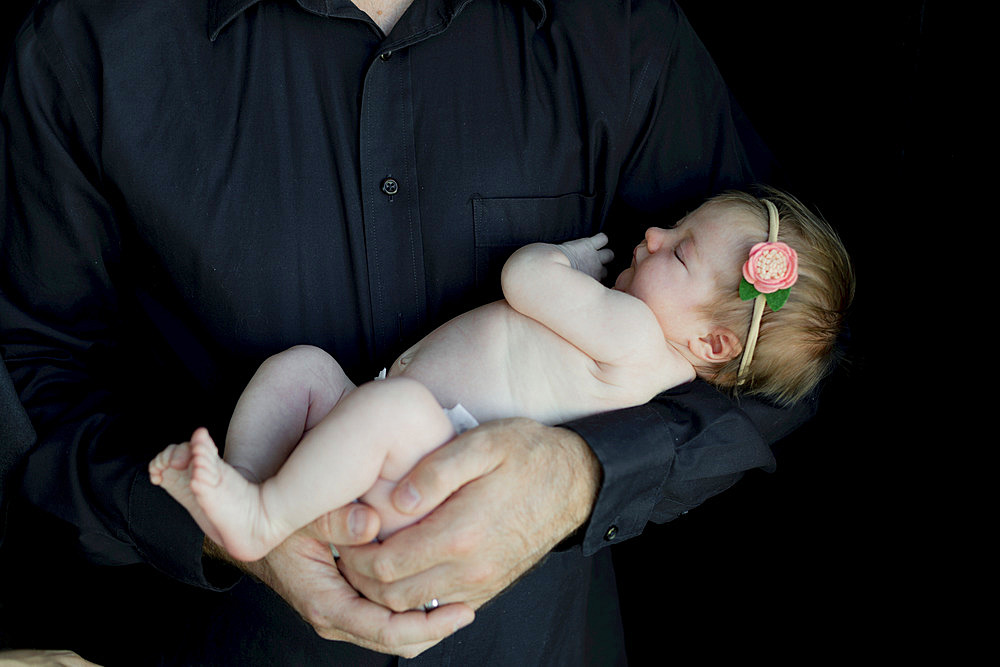 A father holding a newborn infant in his arms; Studio