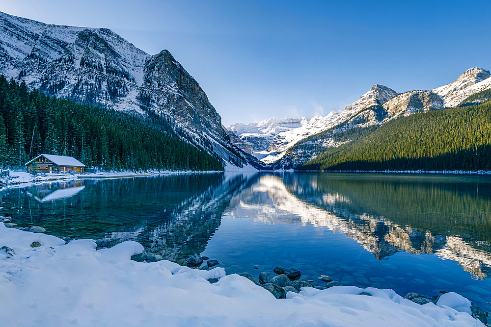 Lake Louise reflecting the Rocky Mountains with snow in autumn, Banff National Park; Alberta, Canada