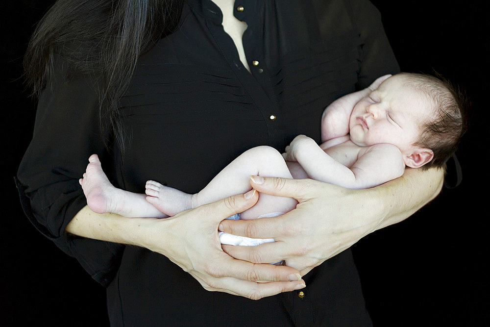 A mother holding a newborn infant in her arms; Studio