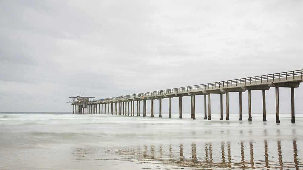 The long expanse of the iconic Scripps Pier in the Pacific Ocean near San Diego on a grey day; La Jolla, San Diego County, California, United States of America