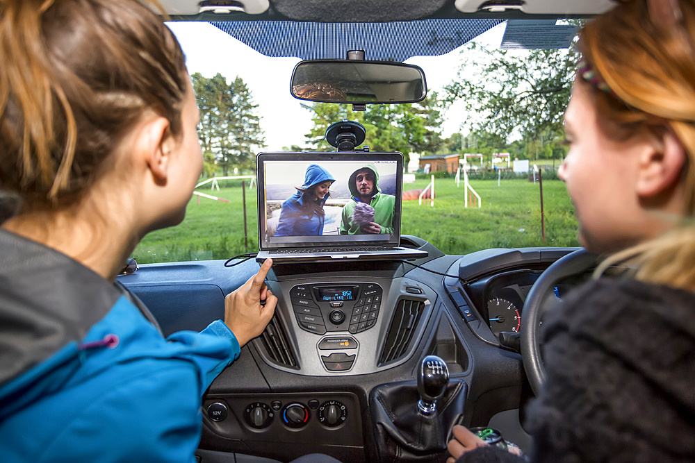 Girls catching up on some videos inside a camper van; Prague, Czech Republic