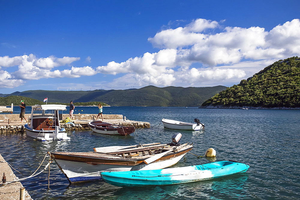 Young adult tourists at the waterfront of Duboka with rowboats and motorboats mooring in the water; Duboka, Dubrovacko-neretvanska zupanija, Croatia