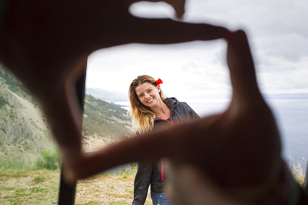 Framing a beautiful girl with fingertips with the Croatian coastline in the background; Pisak, Splitsko-dalmatinska zupanija, Croatia