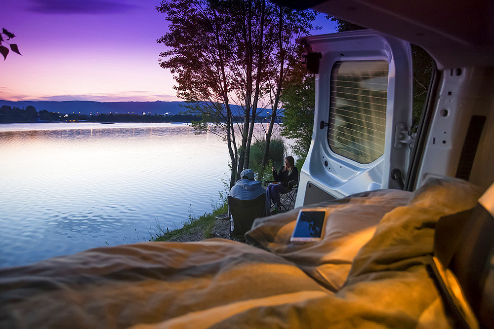 Travelers pull up alongside a lake in Bratislava to free camp for the night. A view from the bed in the back of the camper van; Bratislava, Bratislava Region, Slovakia