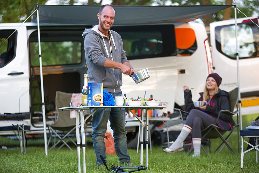 A stop for the night at a Czech Republic campsite between Prague and Cesky Krumlov. The 50 person town is called Kostelec and it is on the outsirts of Hluboka nad Vltavou. A camper prepares dinner for his friends; Kostelec, Vltavou, Czech Republic