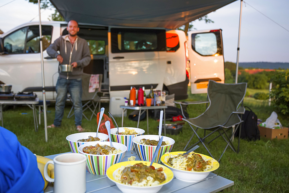 A stop for the night at a Czech Republic campsite between Prague and Cesky Krumlov. The 50 person town is called Kostelec and it is on the outsirts of Hluboka nad Vltavou. A camper sets up dinner at their campsite; Kostelec, Vltavou, Czech Republic