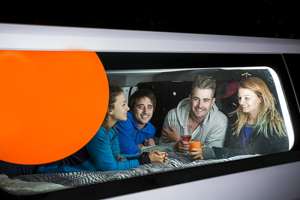 A group free camps for the evening in the German city of Kassel. The group huddles inside the van to play games; Kassel, Kassel, Germany