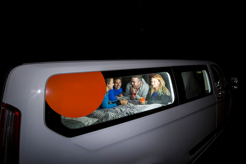 Group of travelers huddled inside their camper van playing games for the evening, free camping in the German city of Kassel; Kassel, Germany