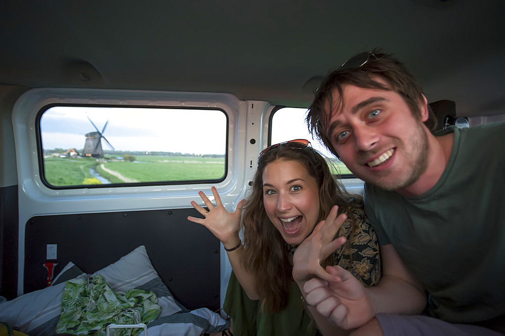 Travelers inside a camper van exploring North Holland searching for iconic windmills outside of Amsterdam Central along the journey to the coastal city of Egmond aan Zee; Holland