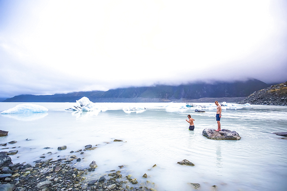 Men swimming in the icy glacial lakes of Mount Cook National Park; Canterbury, New Zealand