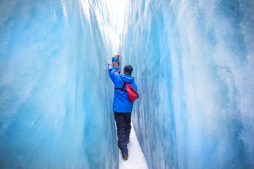 Travellers explore New Zealand's famous Franz Josef Glacier. Blue Ice, deep crevasses, caves and tunnels mark the ever changing ice; West Coast, New Zealand