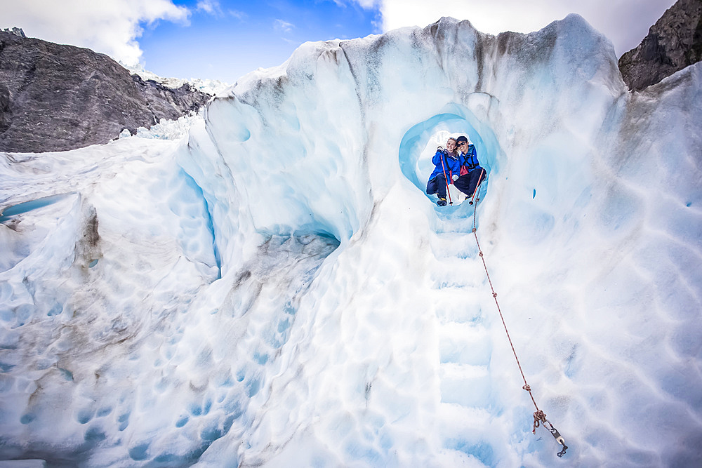 Travellers explore New Zealand's famous Franz Josef Glacier. Blue Ice, deep crevasses, caves and tunnels mark the ever changing ice; West Coast, New Zealand